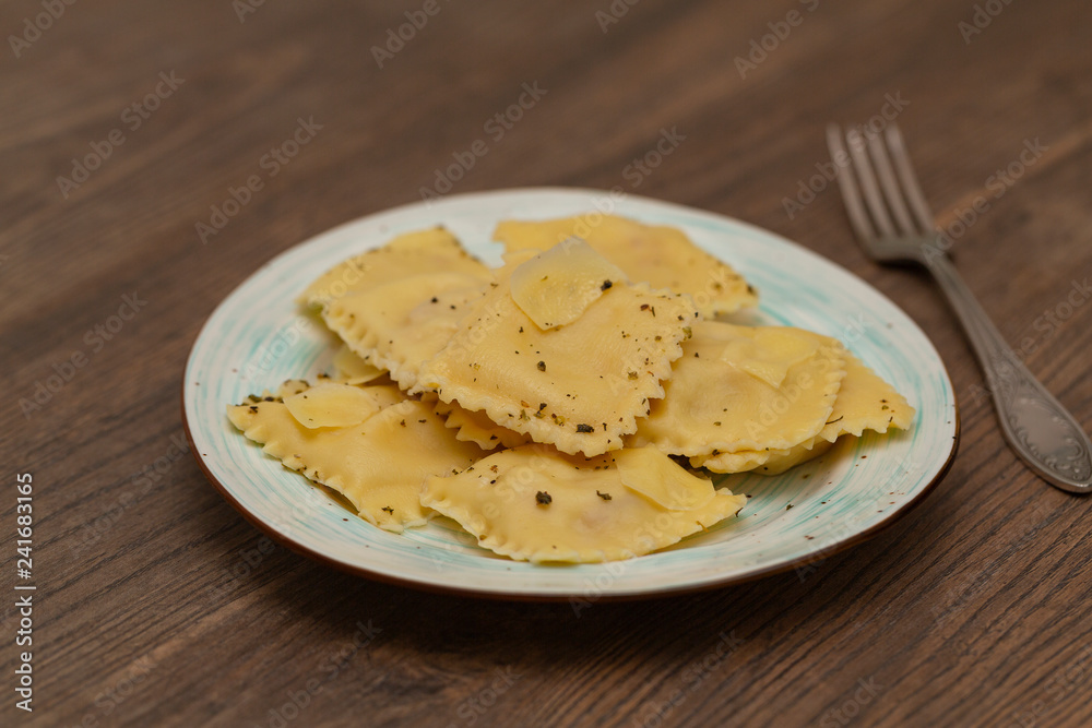 Plate of ravioli with Parmesan on wooden table. Tasty ravioli with Parmesan