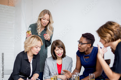 Multicultural Female volunteer s group that help large families, gathered to discuss a new promotion actions, using notebooks , portable computer and a smart-phone during adiscussion.