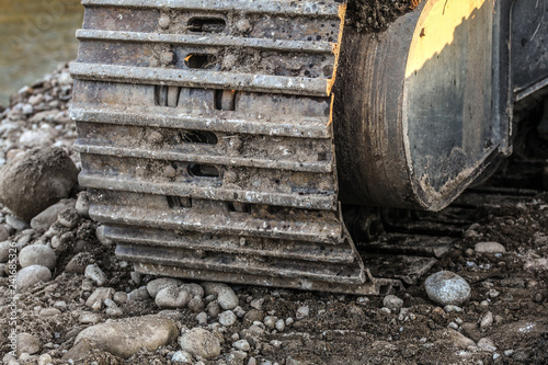 Detail of metal digger track on stones and sand ground. Construction concept.
