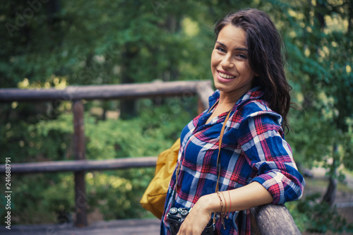 Smiling young woman watching the forest from the balcony of the forest house.