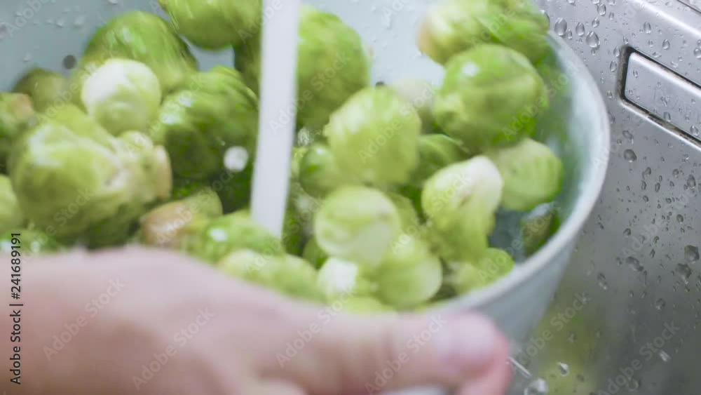 washing raw Brussels sprouts in kitchen sink washing raw Brussels sprouts in kitchen sink