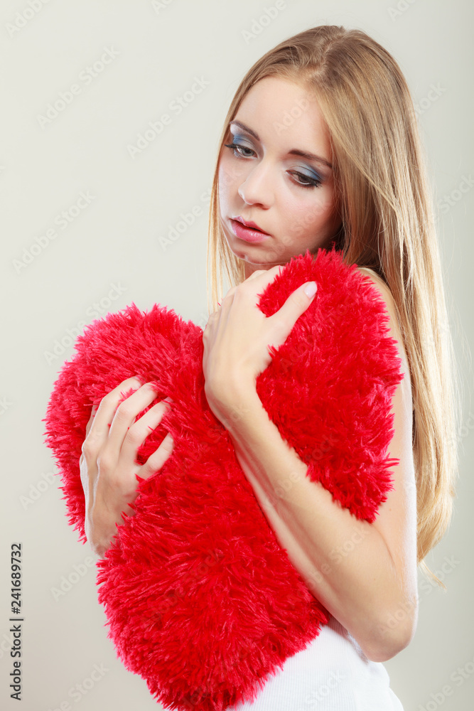 Sad unhappy woman holding red heart pillow Sad unhappy woman holding red heart pillow