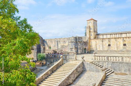 Historical walls and stairs leading to the main church of the portuguese Convent of Tomar with a group of young female tourists. The complex was built by the Templars.