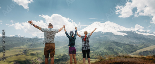 Photography Three friends joined hands and raised their hands up, enjoying the view of the mountains in the summer