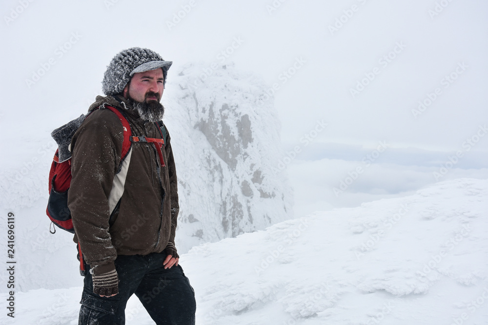 Fototapeta premium Hiker in a winter mountains. Concept of healthy lifestyle and successful climb, hiking in nature. Winter background