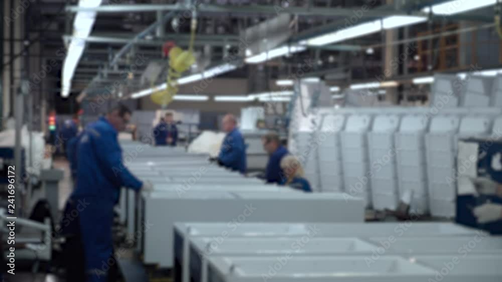 Blurred view of conveyor, masters and workers at work, part assembly process of element refrigerators, household appliances assembly shop. Blurred view of conveyor, masters and workers at work, part assembly process of element refrigerators, household appliances assembly shop.