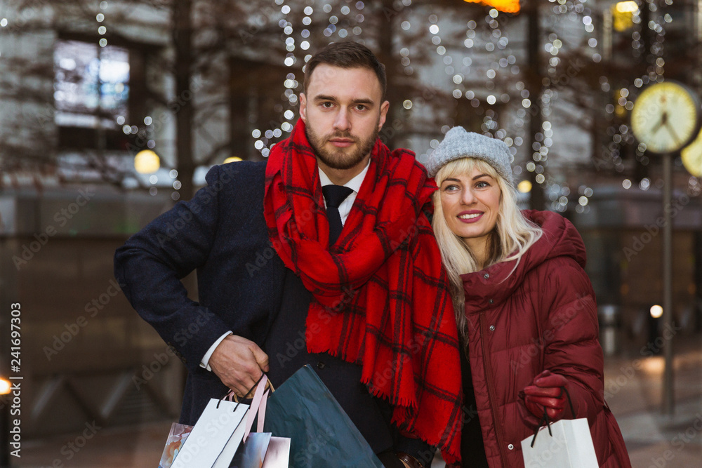 Portrait of the happy young couple who is standing on the street with shopping bags