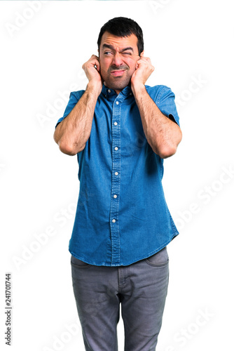 Handsome man with blue shirt covering both ears with hands