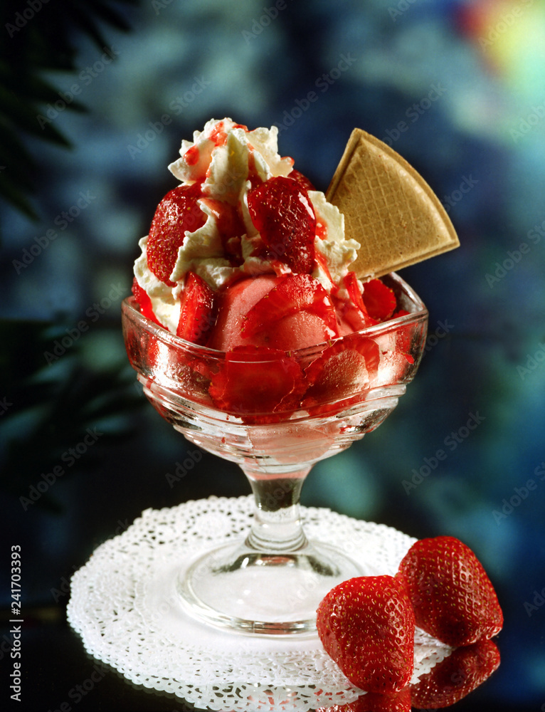 Una copa con dos bolas de helado de fresa y vainilla, y fresas naturales,  nata montada, caramelo líquido y una galleta de adorno. Stock 写真 | Adobe  Stock