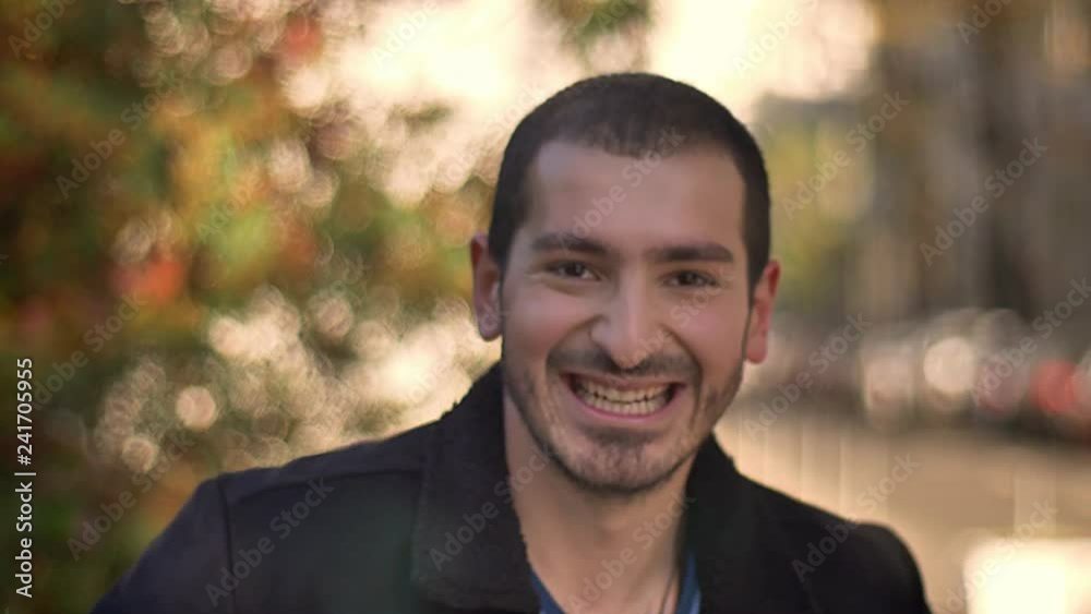 Portrait of young caucasian man smiling joyfully into camera on autumnal street background. Portrait of young caucasian man smiling joyfully into camera on autumnal street background.