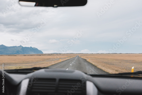 Wallpaper Mural View from inside a car over a long empty road ahead in Iceland with mountains in the background Torontodigital.ca