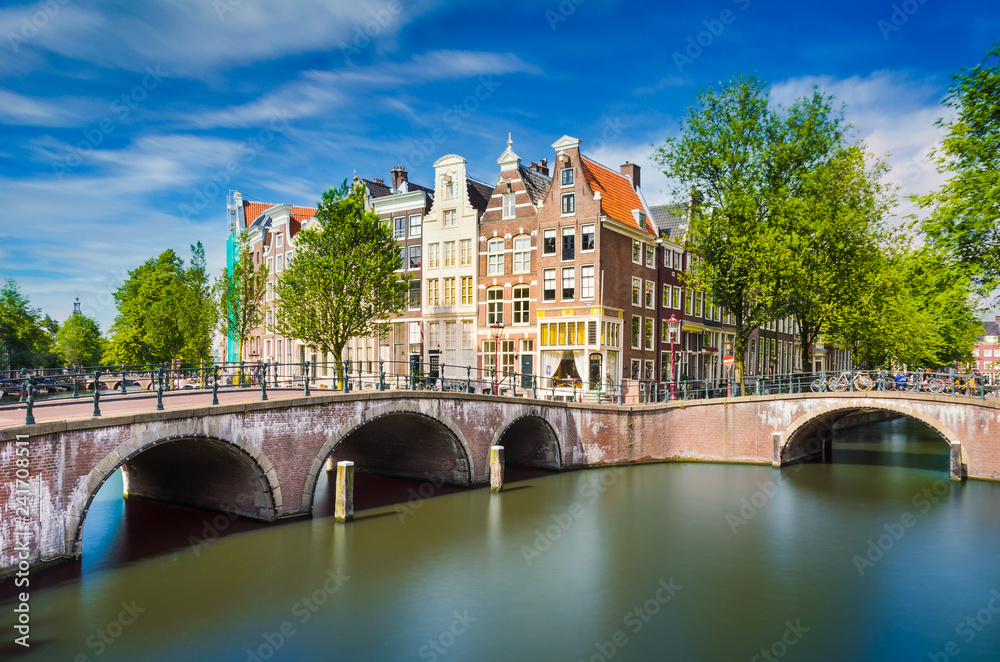 Fototapeta premium Kanał z tradycyjnymi budynkami w Amsterdamie, Holandia
