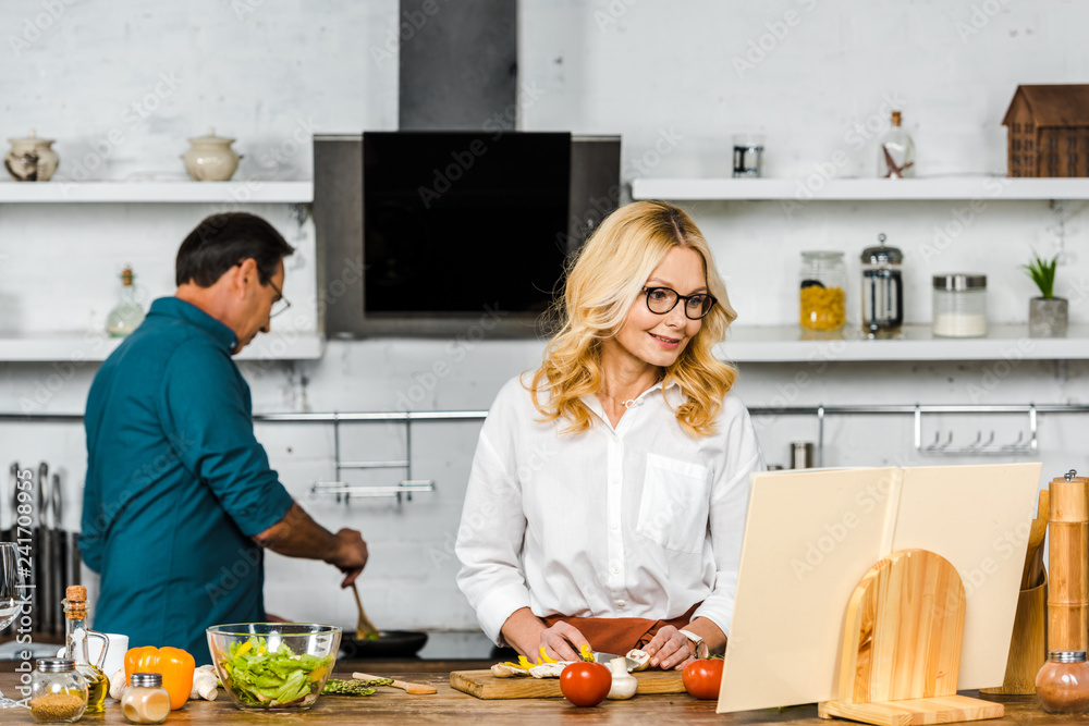 mature wife and husband cooking together in kitchen