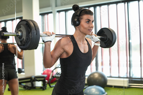 Fitness model performing weight lifting exercise at gym