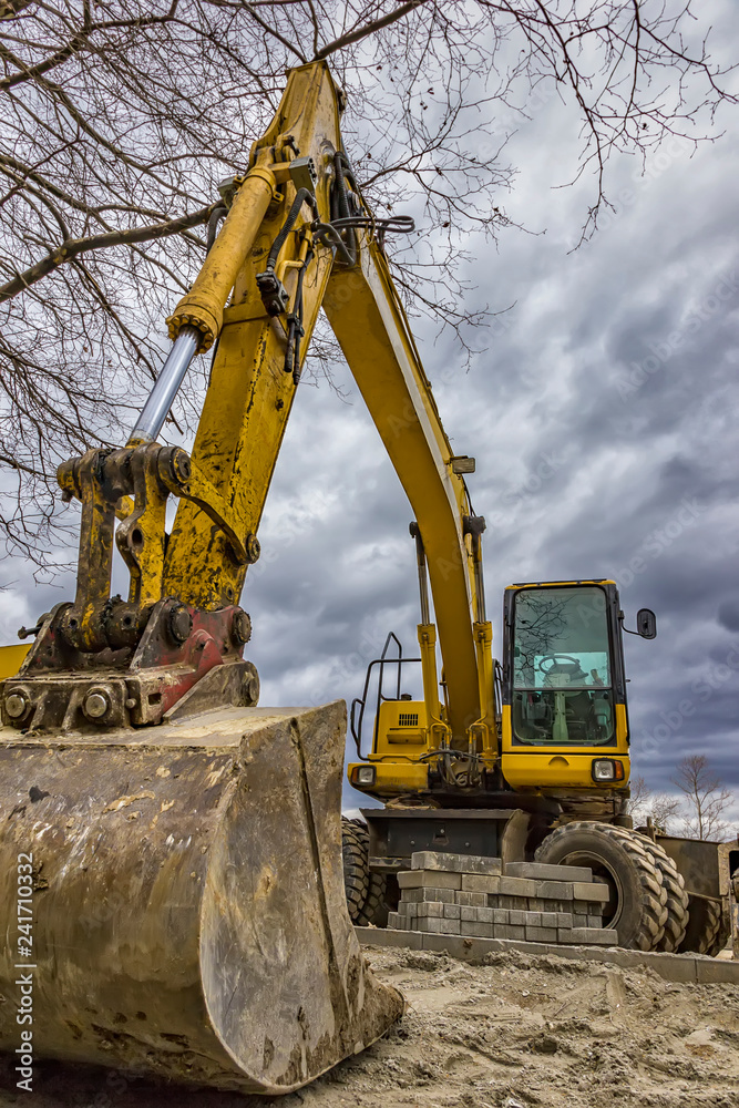 Big yellow stopped excavator at the construction site. Vertical view