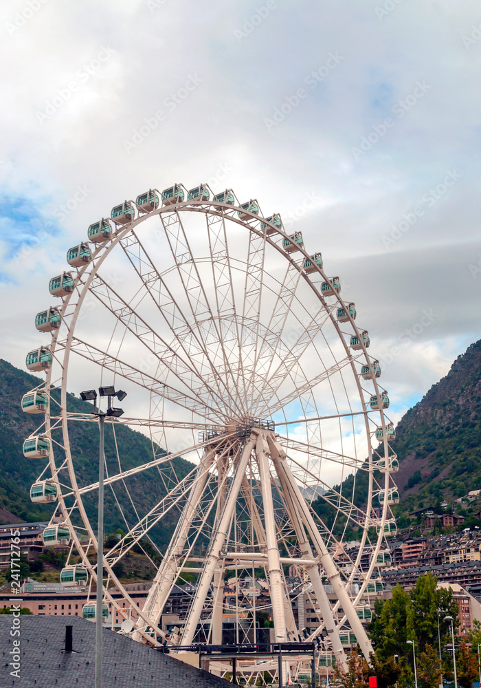 ANDORRA LA VELLA, ANDORRA - SEPTEMBER 2014. Ferris wheel turning in Andorra with the Pyrenees alond mountains