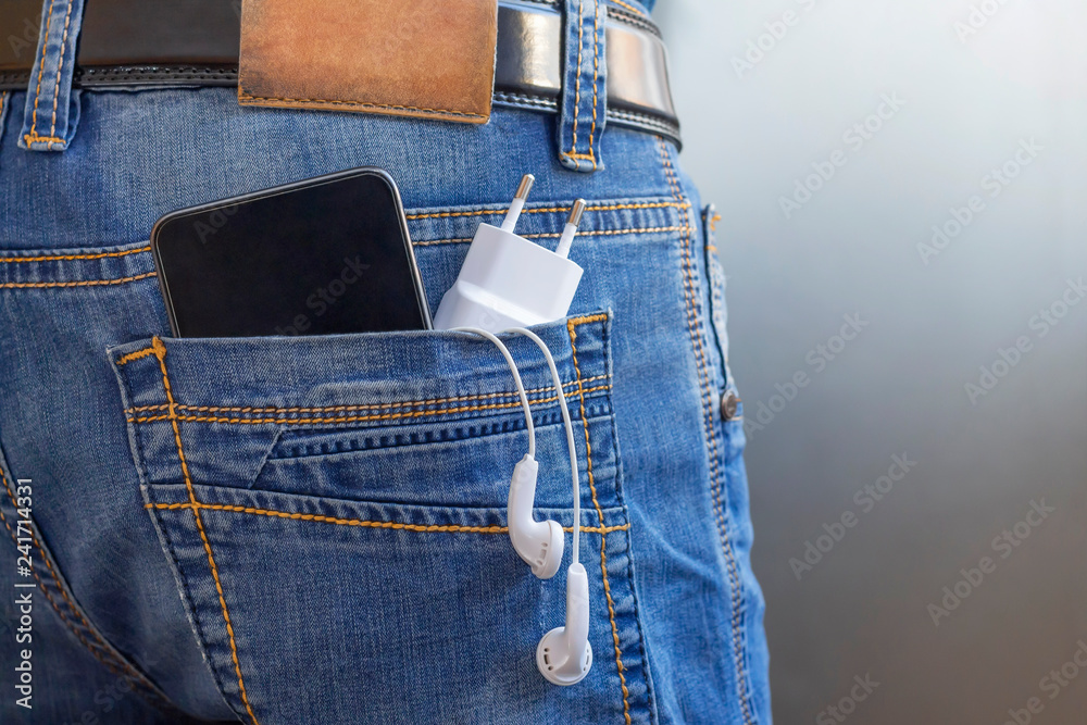 phone charging, smartphone, headphones in jeans pocket. technology in everyday life, battery fast discharge concept