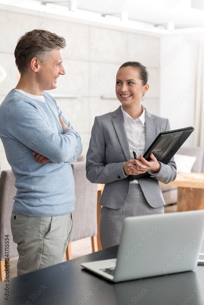 Smiling mature man and saleswoman discussing while standing in apartment Smiling mature man and saleswoman discussing while standing in apartment