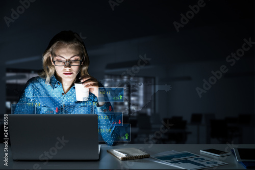 Beautiful blonde working on laptop and infographs out of screen.