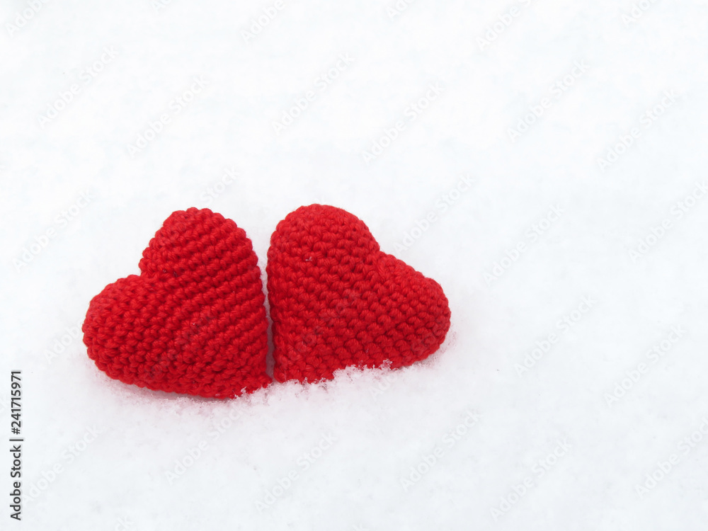 Fototapeta premium Two Valentine hearts in the snow, red knitted symbols of love. Background for Valentines day greeting card, concept of romantic celebration