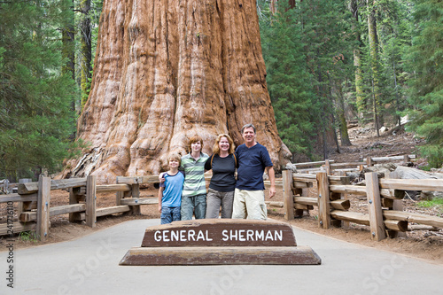 happy family enjoys posing in sequoia national park in front of general sherman sequoia tree photo