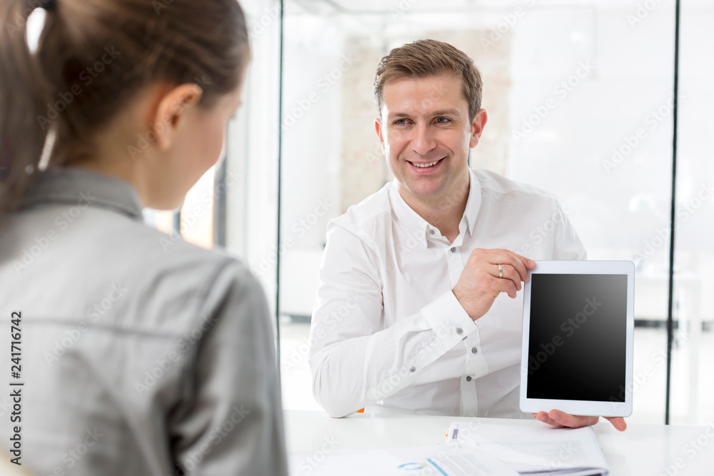 Creative businessman showing digital tablet to colleague in office Creative businessman showing digital tablet to colleague in office