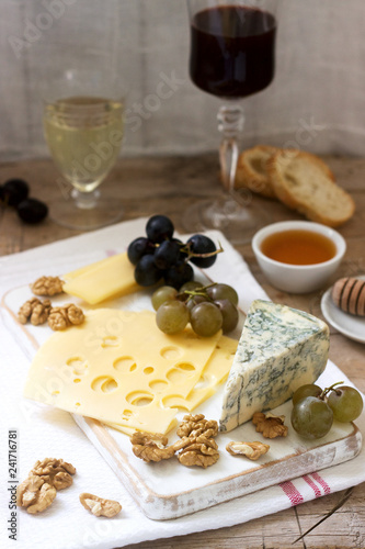 Appetizers of various types of cheese, grapes, nuts and honey, served with white and red wine. Rustic style.