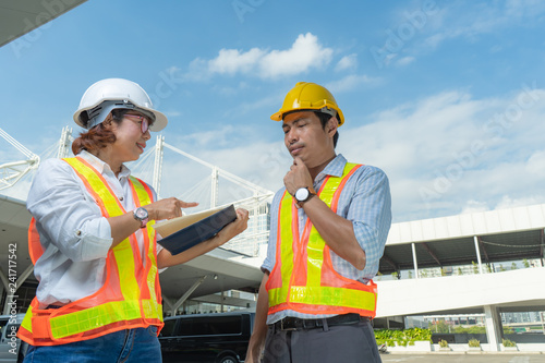 Male and Female Industrial and civil engineers wear personal protective equipment, discuss the end of project and working in project site.partnership agreement, teamwork and business concept,