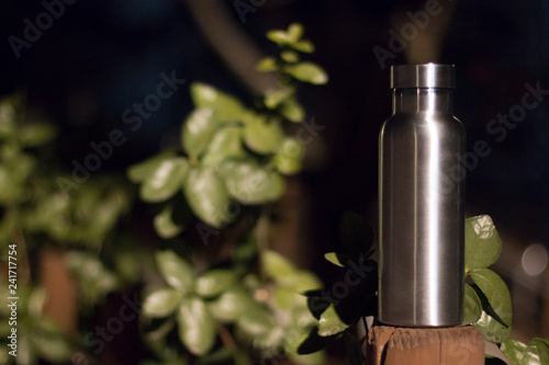 an insulated stainless steel bottle at the forest in the night