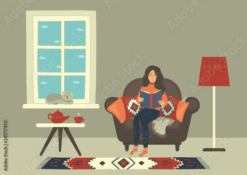 Woman in cozy armchair reading book and drinking hot tea