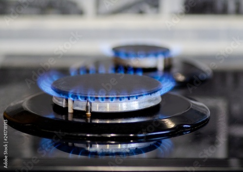 Natural gas burning on kitchen gas stove in the dark. Panel from steel with a gas ring burner, close-up shooting