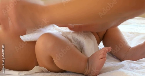 Mother changing diaper on her newborn baby in nursery