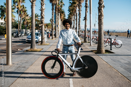 Mid adult man standing on the road, showing his fixie bike photo