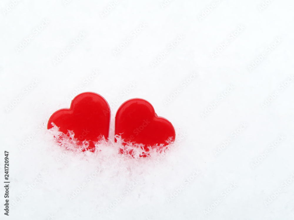 Fototapeta premium Two red hearts in the snow, Valentine day. Symbols of love, background for romantic greeting card with free copy space