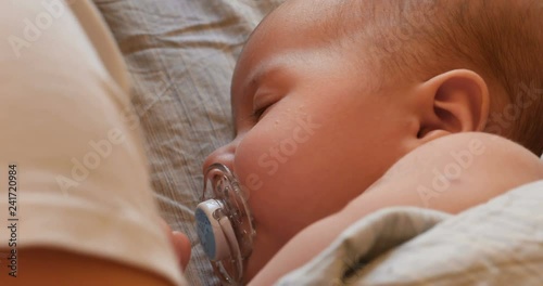 Top view of cute two month old baby with soother lying on back and sleeping