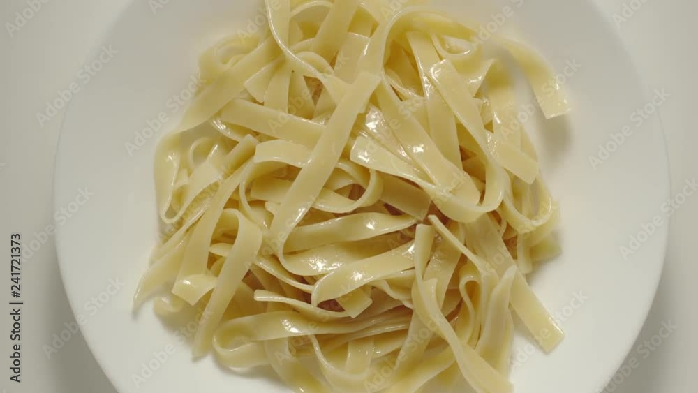 SLOW MOTION: Fettuccine pasta falling into a white plate - Top View SLOW MOTION: Fettuccine pasta falling into a white plate - Top View