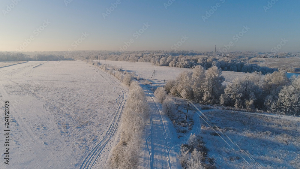 aerial view winter landscape countryside road through winter field with forest. winter forest on sunny day. winter in countryside