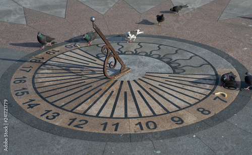 Sundial with pigeons on the waterfront of the city