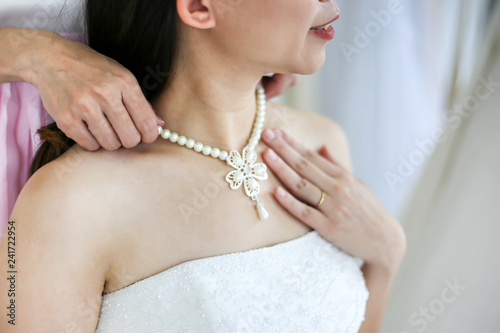 Beautiful bride getting dressed by her best friend in her wedding day and choosing a wedding dress in the shop and the shop assistant is helping her