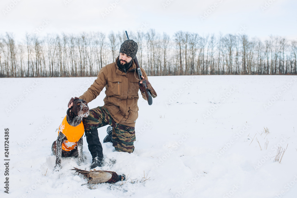 pleasant man is thanking his dog for help during hunting. full length photo. copyspace. rest, excellent weather for hunting