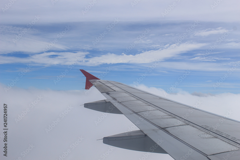 Obraz premium Wing of an airplane flying above the clouds