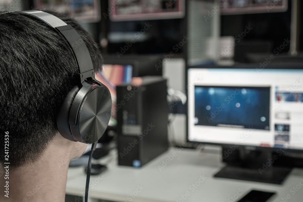 Education e-learning foreign languages Concept : Asian Student Young man wearing Headphones listening English songs music and searching for learning abroad in computer pc at classroom of university