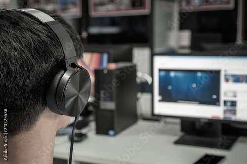 Education e-learning foreign languages Concept : Asian Student Young man wearing Headphones listening English songs music and searching for learning abroad in computer pc at classroom of university