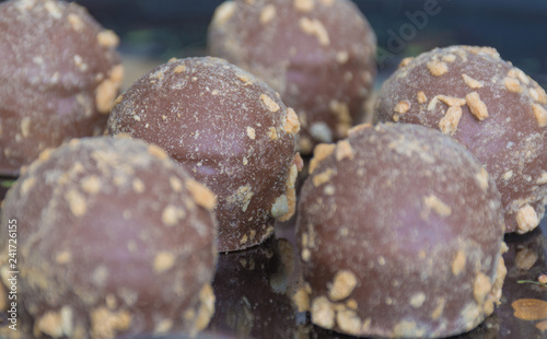 Closeup chocolate candies truffles on dark plate. Side view. Food photography concept