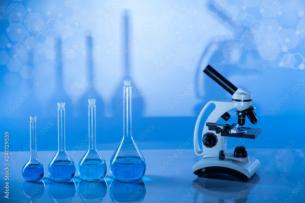 Laboratory beakers, microscope, blue background