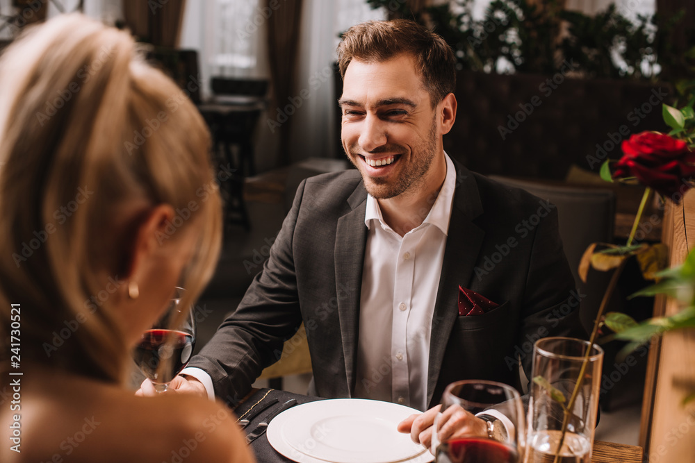handsome man laughing in restaurant while looking at woman handsome man laughing in restaurant while looking at woman