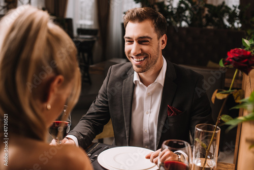 handsome man laughing in restaurant while looking at woman