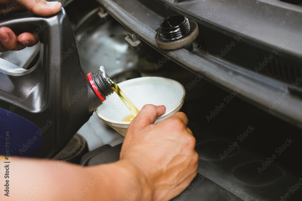mechanic pouring oil to vehicle engine. serviceman changing motor oil in automobile repair service. maintenance & checkup in car garage