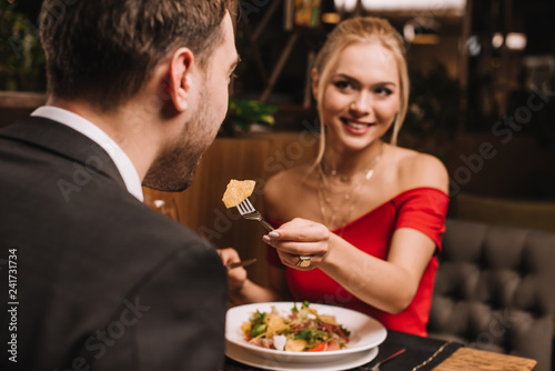 attractive girlfriend feeding boyfriend in restaurant