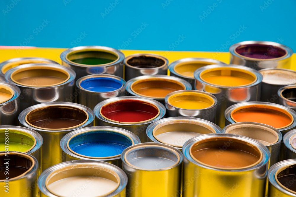 Full Buckets of rainbow colored oil paint on blue background Full Buckets of rainbow colored oil paint on blue background
